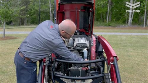 man working on red yt 235 yanmar tractor