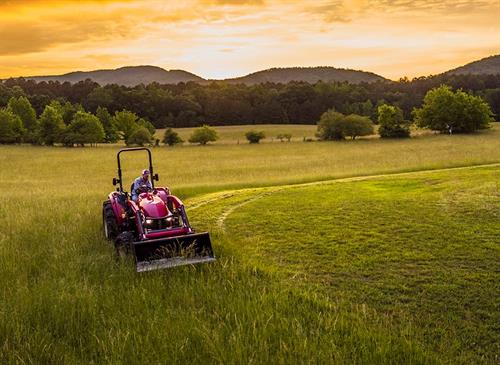 yanmar yt359 compact tractor driving through grassy area